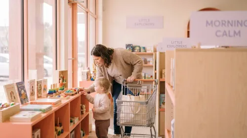 A parent and toddler browse a calm, modern store designed around retail innovation in soft morning light